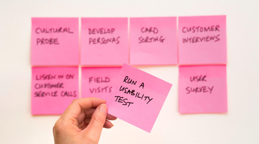 Collection of pink sticky notes on a wall with one being picked up